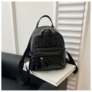 Close-up of black quilted mini backpack featuring gold hardware and bow zipper pulls