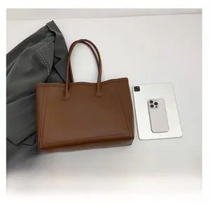 Braune Shopper-Tasche aus Leder im Größenvergleich zu einem Tablet und Smartphone