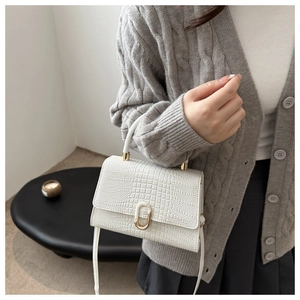 Close-up of white crocodile pattern handbag with elegant gold ring buckle and leather handle