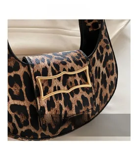 Detailed close-up of leopard print texture and wavy golden metallic buckle on the handbag