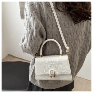 Detailed back view of a white crocodile embossed handbag with golden buckle and metal handle