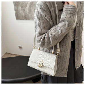 Close-up of white crocodile pattern bag with golden oval buckle and shoulder strap