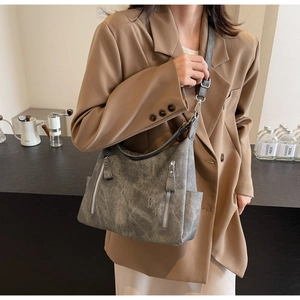 Detail of dark grey retro textured tote bag with multiple zipper pockets on casual outfit