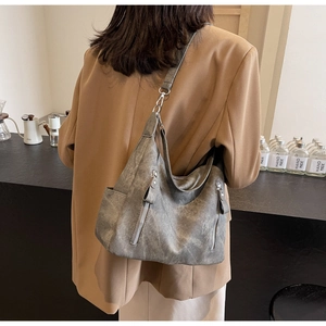 Close-up of a large grey hobo bag with matte texture and dual vertical zipper pockets