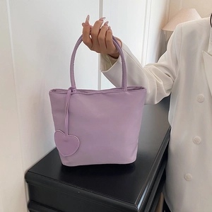 Minimalist light purple nylon tote bag with heart charm shown in a fashion lifestyle setting