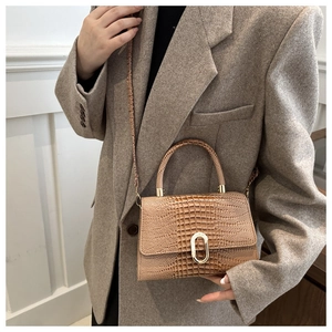 Detail of tan crocodile embossed bag featuring a gold buckle on a grey tweed blazer