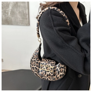 Close-up of leopard print crescent bag with gold metal buckle on black wool coat