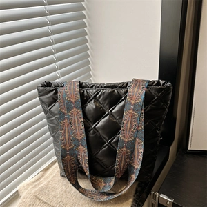 Sac fourre-tout matelassé noir avec bandoulière ethnique sur surface en tricot