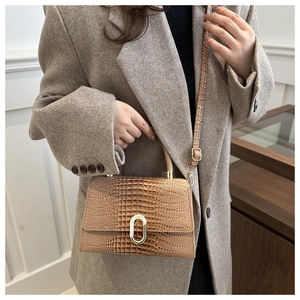 Close-up of brown croc-effect handbag with gold lock and ethnic woven shoulder strap