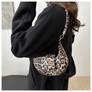 Detail of leopard print crescent bag with gold buckle on black wool coat for women