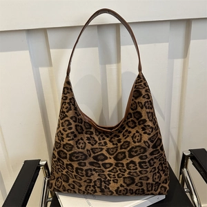Chic leopard print faux suede tote bag with brown leather trim on a modern chair