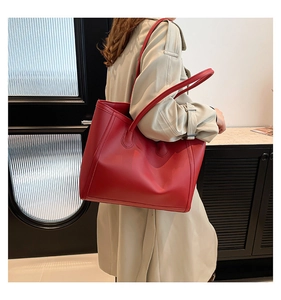 Nahaufnahme einer großen roten Ledershopper-Tasche kombiniert mit einem beigen Trenchcoat