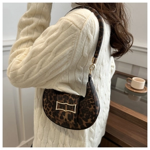 Close-up of leopard print crescent bag with golden H buckle on a cozy knit sweater