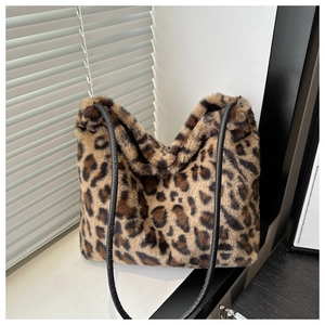 Gros plan sur un sac cabas en peluche léopard avec des anses noires sur un rebord