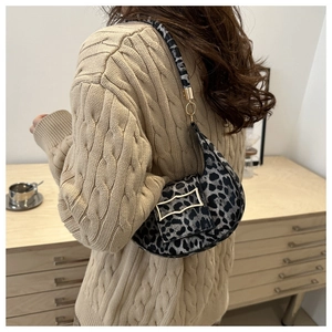 Close-up of leopard print crescent bag with gold metal buckle on a cozy beige sweater