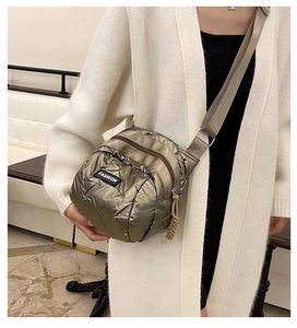 Detail view of metallic quilted crossbody bag with multiple zip compartments and fabric strap