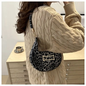 Detail of leopard print hobo bag with gold metal clasp on model wearing beige knitwear