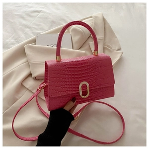 Detail of rose pink crocodile embossed handbag with a gold oval metal lock and strap