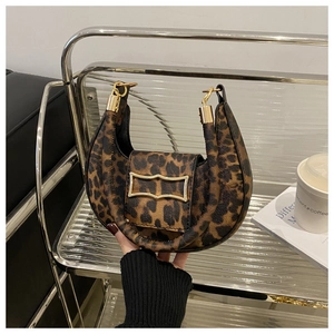 Detail of leopard print crescent bag with golden geometric clasp held in hand