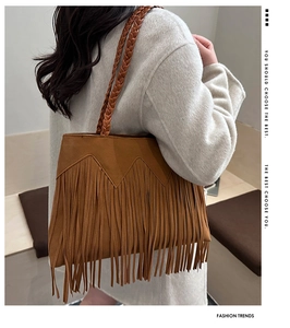 Detail of bohemian brown suede tote bag with long fringes and woven handles worn by model