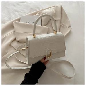 Detailed close-up of white crocodile pattern texture and gold U-shaped metal buckle on the bag