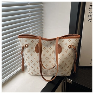 Detail shot of a large tote bag featuring vintage monogram print and brown leather handles