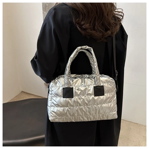 Détail d'un sac bouffant argenté métallisé matelassé porté à l'épaule sur un manteau