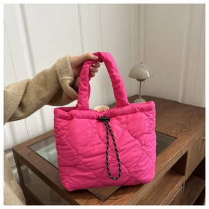 Detail of pink quilted tote bag with heart patterns and black drawstring closure