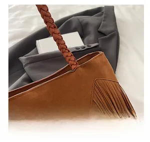 Detailed close-up of brown suede tassel bag with intricate woven handle design
