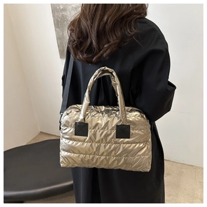Sac Boston matelassé chic en or champagne métallisé porté à l'épaule pour femme