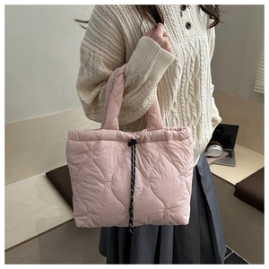Detail of pink quilted tote bag with heart embroidery and black drawstring closure