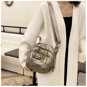 Detail of metallic bronze quilted crossbody bag with adjustable strap and fashion label