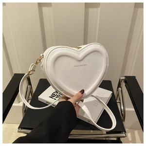 Detail view of heart-shaped white crossbody bag with embossed patterns and gold lettering