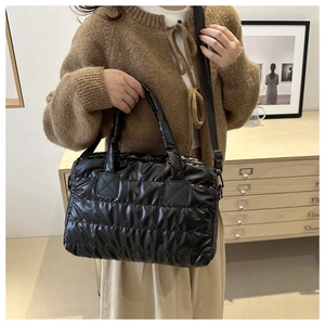 Détail d'un sac à bandoulière matelassé noir avec sangle en nylon dans un décor de maison