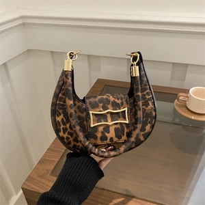 Elegant leopard print crescent handbag with gold buckle in a cozy cafe setting