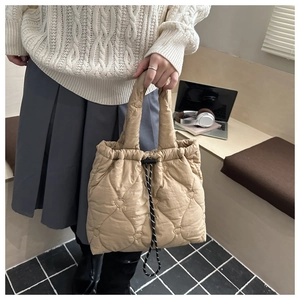 Detail view of quilted heart pattern on beige tote bag in a casual office setting
