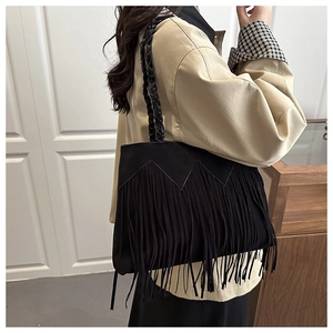 Detail view of black tassel shoulder bag with woven handle and fringe decor