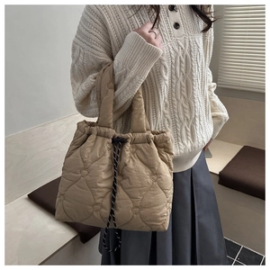 Detail of beige heart-quilted puffer tote bag with drawstring and woven rope handles