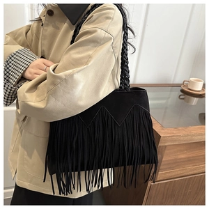 Close-up of black suede bucket bag featuring long bohemian tassels and woven rope handle