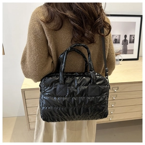 Détail du sac à main matelassé noir brillant avec poignées et bandoulière amovible