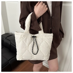 Detailed view of white quilted tote bag featuring heart embroidery and drawstring closure