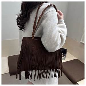 Detail of dark brown suede tote bag featuring long fringes and woven leather shoulder strap