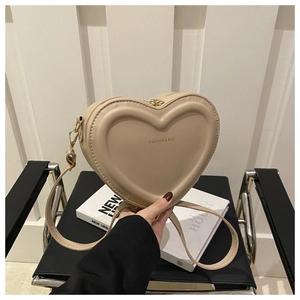 Detailed view of heart-shaped crossbody bag in beige featuring embossed leather texture