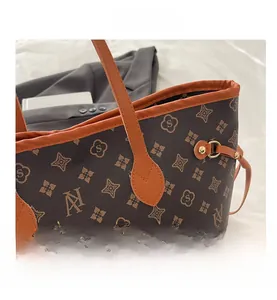 Detail of monogram tote bag with brown synthetic leather and orange trim handle