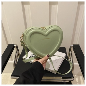 Detail of light green heart-shaped shoulder bag with gold lettering and zipper