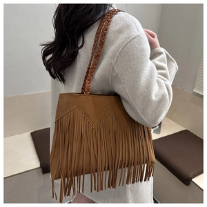 Detail of a brown fringe tote bag featuring woven straps and soft faux suede material