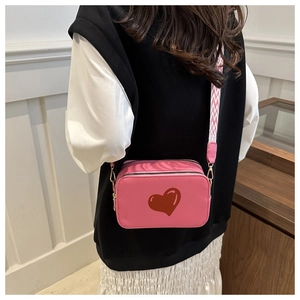 Pink faux leather crossbody bag with red heart print shown on model for daily styling