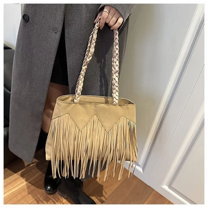 Close-up of khaki suede bag featuring long fringe tassels and woven leather handles