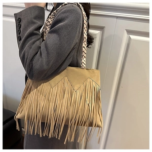 Close-up of bohemian brown suede tote bag with fringe details and woven strap