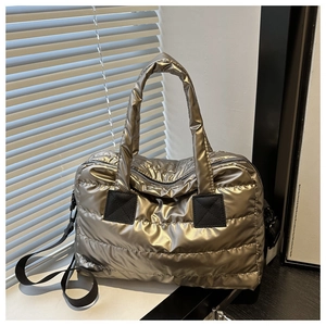 Détail du motif matelassé horizontal sur sac bouffant doré métallisé avec finitions noires